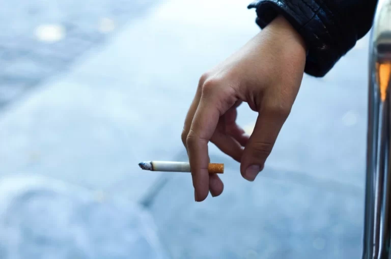 Imagem de uma mão segurando num cigarro acesso