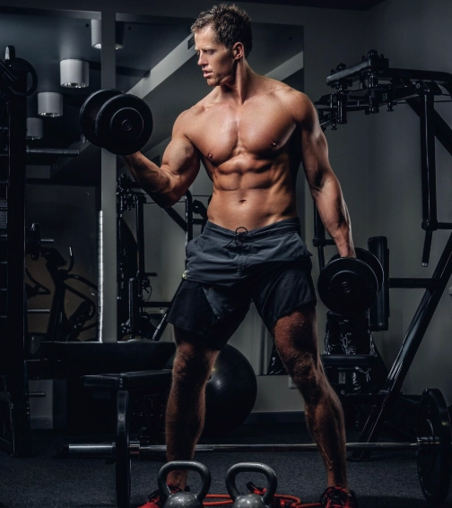 Imagem de um homem a treinar num ginásio, com um halter em cada mão